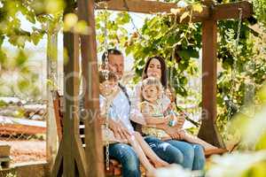 Nothing can replace that precious family time. a family of four relaxing together on a garden swing.