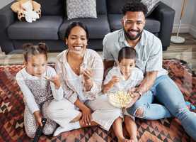 Watching movie, family bonding and eating popcorn while relaxing in the lounge together at home. Happy, smiling and carefree parents enjoying snack, looking at comedy series, laughing with kids