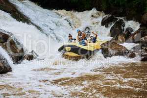 This how we do extreme. a group of determined young men on a rubber boat busy paddling on strong river rapids outside during the day.