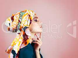 What can she be thinking about. Studio shot of a confident young woman wearing a colorful head scarf while posing against a pink background.