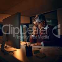 I need the strength to get through these deadlines. a mature businesswoman looking stressed out while working late in an office.