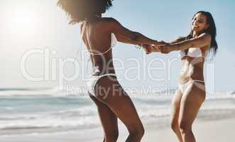 Live everyday as if it were summer. two young women enjoying a playful moment on the beach.