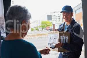 Making payment the efficient way. a handsome young man delivering a package to a customer and receiving payment with a card.