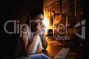 Pushing through her health concerns for the sake of success. a young businesswoman blowing her nose while working late in an office.