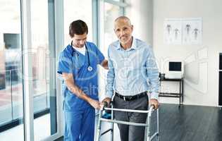 Feels great to be hitting the road to recovery. Portrait of a senior patient with a walker getting assistance from a male nurse.