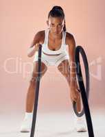 Exercise, fitness goals and active woman exercising with heavy battle ropes in a studio. Portrait of a serious and athletic female working out and doing weight training for a healthy and fit body