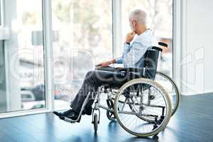 Taking a moment to ponder by himself. a mature man sitting in a wheelchair and looking out the window.