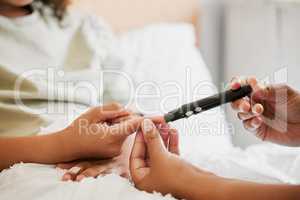 Diabetes, diabetic and mother testing blood sugar levels of a child with a chronic disease at home. Closeup of mom measuring, checking and monitoring glucose in her kid in bed or in the bedroom