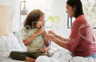 Loving mother comforting her daughter with a bandaid in bed, being affectionate and caring at home. Young parent helping her sick child, applying a plaster and bonding, special moments of motherhood