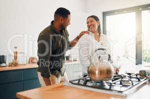 Joyful and loving couple bonding and having fun while spending time together in the kitchen. Smiling, in love and carefree couple laughing, sharing a romantic moment while enjoying the morning