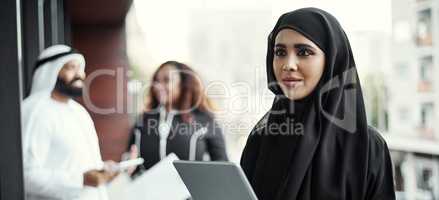 This is how she does business. an attractive young businesswoman dressed in Islamic traditional clothing using a tablet on her office balcony.