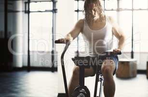 Hes feeling the burn. a handsome young man working out on an elliptical trainer in the gym.