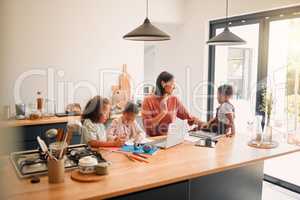 Caring parent tutoring and teaching her small children with after school activity. Loving mother taking care of young kids and helping with class homework projects in the kitchen of their family home