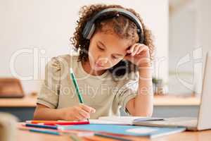 Smart school child, student virtual learning while writing in her book inside an education classroom. Creative with headphones drawing art on paper. Cute, artistic little kid doing homework