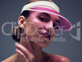 Shes not about blending in with the crowd. Studio shot of an attractive young woman wearing a pink retro cap posing against a gray background.