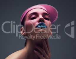 Be you, be unique. Studio shot of an attractive young woman wearing a pink retro cap posing against a gray background.