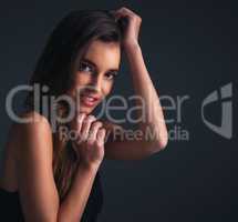 Her charismatic confidence will charm you. Studio shot of an attractive young woman posing against a dark background.