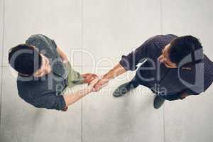 Glad to do business with you. High angle shot of two young businessmen shaking hands in agreement inside of the office during the day.