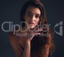 Long and luscious hair to bear. Studio shot of an attractive young woman posing against a dark background.