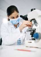 Every sample is vital to her study. a young scientist using a microscope in a lab.