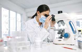 Science is but an image of the truth. a young scientist using a microscope in a lab.