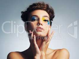 Eye makeup that makes an impact. Studio shot of an attractive young woman with brightly colored makeup against a gray background.