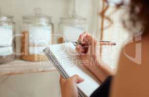 Budget planning, making shopping list and managing household expenses to save money. Financial accountability at home. Woman making shopping list for groceries on a notebook to plan a meal for dinner