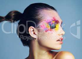 She prefers her makeup on the bold side. Studio shot of an attractive young woman with brightly colored makeup against a blue background.