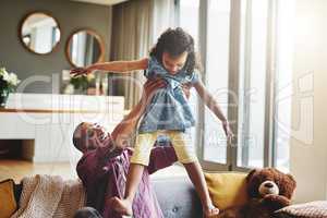 Its playtime between father and daughter. an affectionate young father lifting his daughter playfully in their living room at home.