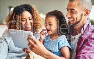 Quality time for the modern family. an adorable little girl and her parents using a digital tablet together on the sofa at home.