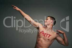 He has one thing on his mind right now. Studio shot of a cheerful young shirtless man standing and flexing his muscles with the word party written on his chest.