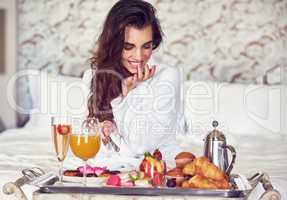 This is a meal fit for a Queen. an attractive young woman enjoying a luxurious breakfast in her room.