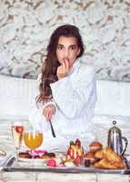 Im all about that good life. an attractive young woman enjoying a luxurious breakfast in her room.