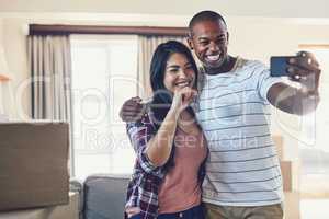 Guess who just got the keys. a young couple taking a selfie in their new home.