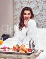 I love a healthy breakfast. an attractive young woman enjoying a luxurious breakfast in her room.