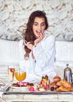 I just cant resist good food. an attractive young woman enjoying a luxurious breakfast in her room.