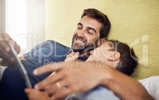 Bonding time in the digital age. a young man using a digital tablet with his son at home.