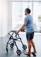 Making great progress. a handsome mature man pushing a walker to help rehabilitate his movement at a clinic.