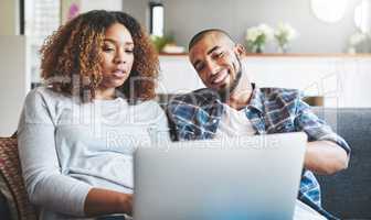Technology gives couples more ways to connect. a young couple relaxing on the sofa at home and using a laptop together.