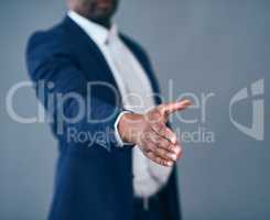 To starting new business ventures. Studio shot of an unrecognizable corporate businessman putting his hand out for a handshake against a gray background.