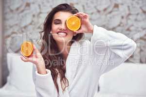 I see some vitamin C. an attractive young woman holding up orange halves.