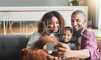 Family time is the best time for a selfie. an adorable little girl taking selfies with her parents at home on a mobile phone.