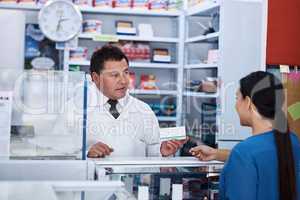 For recovery from your illness take this. a male pharmacist helping a female customer in a pharmacy.