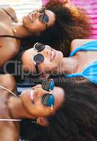 Beating the heat with the besties. a group of happy young women wearing sunglasses and relaxing at the beach.
