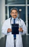The app for doctors endorsed by a doctor. Portrait of a mature doctor holding up a digital tablet with a blank screen in a hospital.