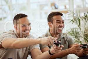 Smiling male friends playing video game console and having fun, hanging out together at home. Young men holding joystick controllers being playful and enjoying their free leisure break time