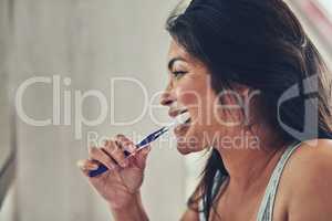 Brush daily for a sparkling smile. an attractive young woman brushing her teeth at home.