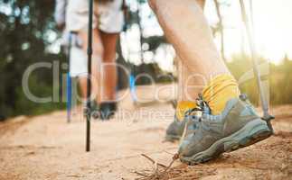 . Feet or shoes walking, trekking and hiking on a trail up a mountain with sticks and poles. Closeup of group of adventurous hikers or friends exploring rugged path on a mountain in nature.