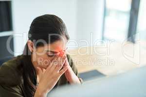 Hit by another headache. a young businesswoman suffering with a headache in an office.