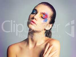 Makeup that reflects all of her true colors. Studio shot of an attractive young woman with brightly colored makeup against a gray background.